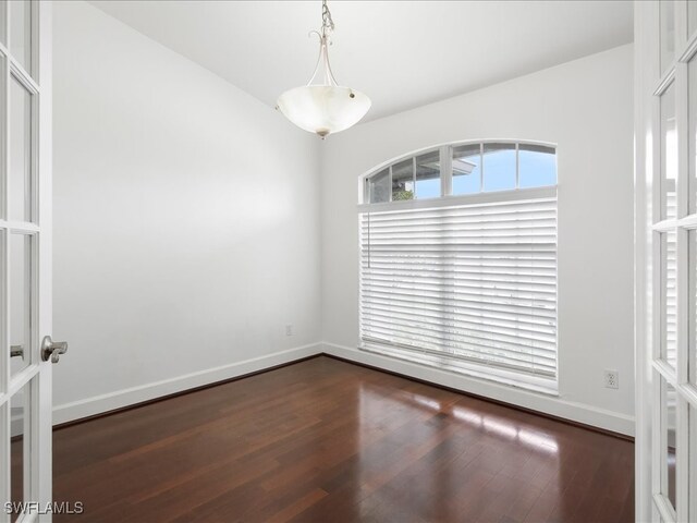 empty room with dark hardwood / wood-style floors and french doors