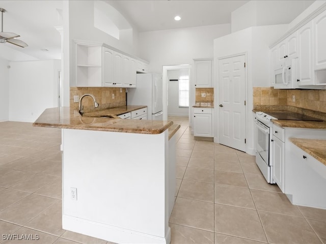 kitchen with kitchen peninsula, white appliances, sink, white cabinets, and light tile patterned flooring