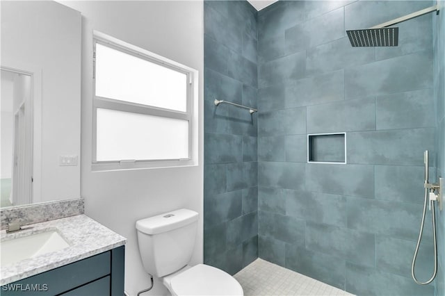 bathroom with tiled shower, vanity, and toilet