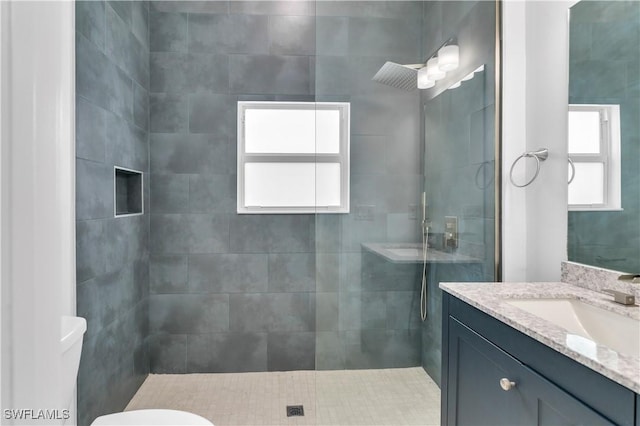 bathroom featuring tiled shower, plenty of natural light, vanity, and toilet