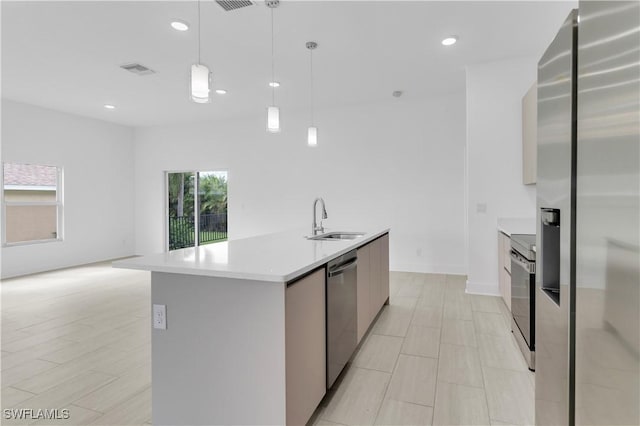 kitchen with hanging light fixtures, sink, stainless steel appliances, and a kitchen island with sink