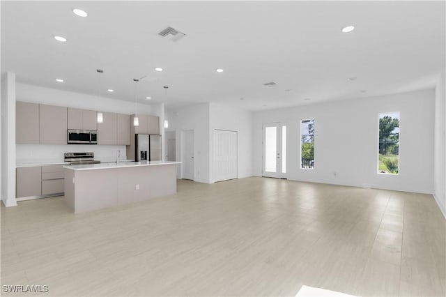 kitchen featuring pendant lighting, stainless steel appliances, gray cabinetry, and an island with sink