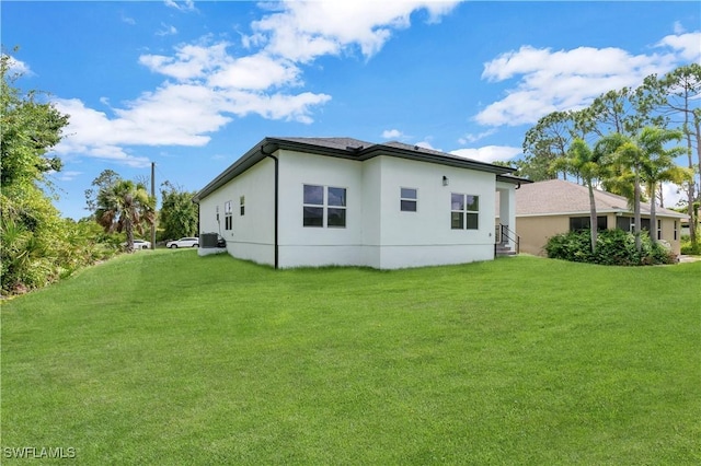 rear view of house featuring a lawn and central air condition unit