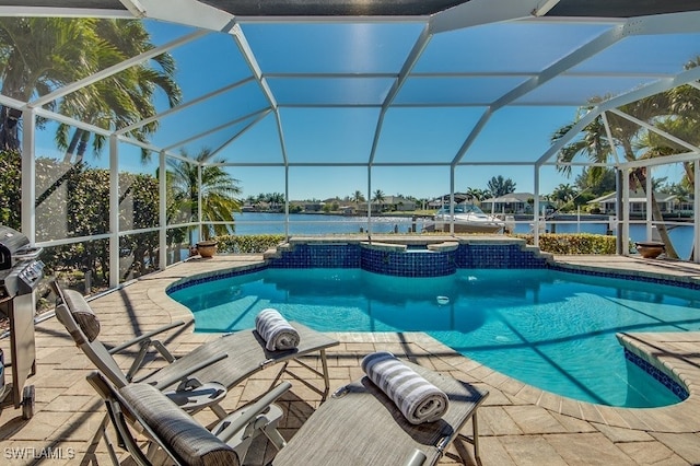 view of pool with glass enclosure, a patio area, and a water view