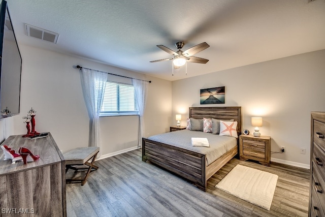 bedroom featuring ceiling fan, a textured ceiling, and light hardwood / wood-style flooring