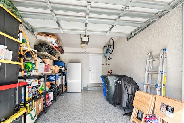 garage featuring white refrigerator and a garage door opener