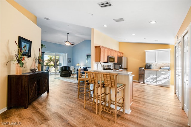 kitchen featuring ceiling fan, light hardwood / wood-style floors, vaulted ceiling, and appliances with stainless steel finishes