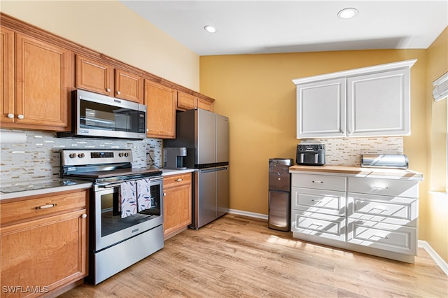 kitchen with appliances with stainless steel finishes, backsplash, light hardwood / wood-style floors, and vaulted ceiling