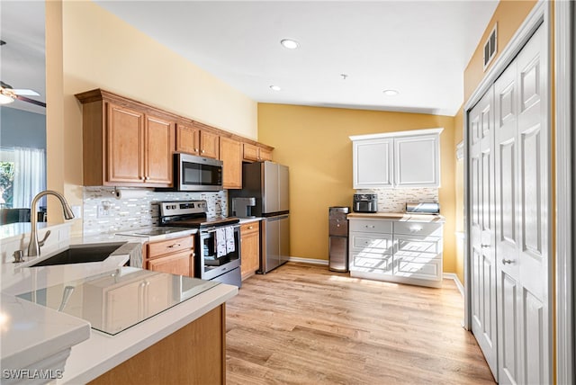 kitchen with sink, tasteful backsplash, vaulted ceiling, appliances with stainless steel finishes, and light wood-type flooring