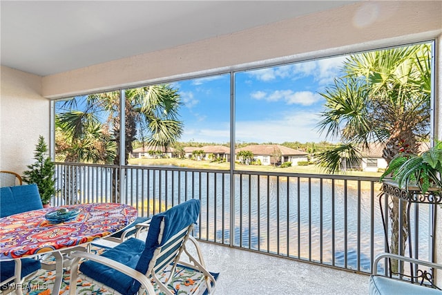 sunroom featuring a water view