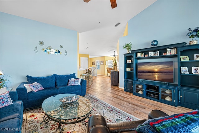 living room featuring ceiling fan, hardwood / wood-style floors, and vaulted ceiling