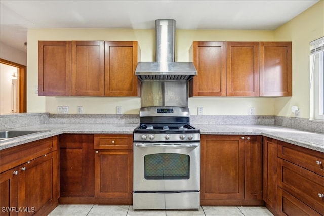 kitchen featuring light stone countertops, wall chimney range hood, light tile patterned floors, and stainless steel gas range