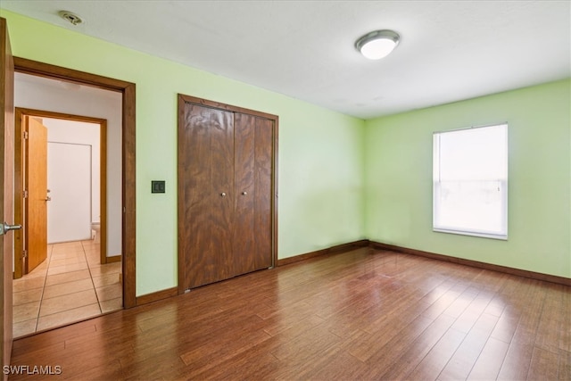 unfurnished bedroom with light wood-type flooring and a closet