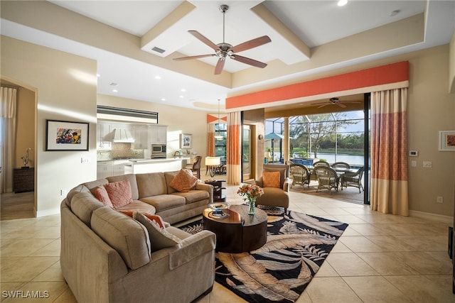 living room with light tile patterned floors, a tray ceiling, and ceiling fan