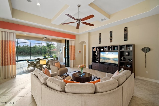 living room featuring a water view, ceiling fan, beamed ceiling, and light tile patterned floors