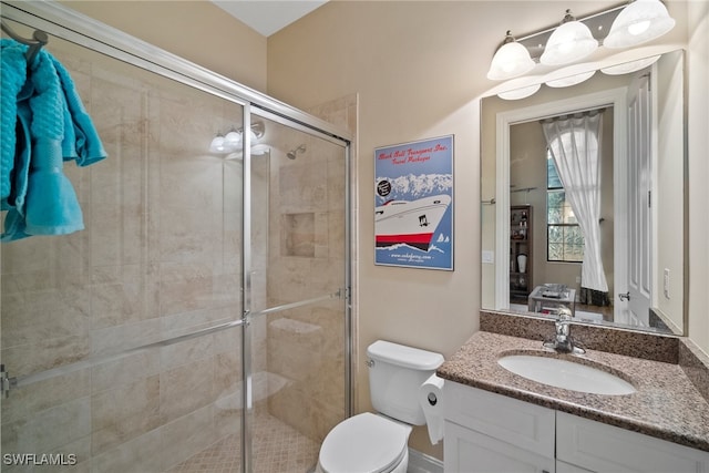 bathroom featuring a shower with door, vanity, and toilet