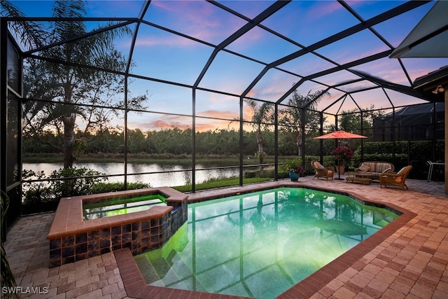 pool at dusk featuring an in ground hot tub, a patio, a water view, and glass enclosure