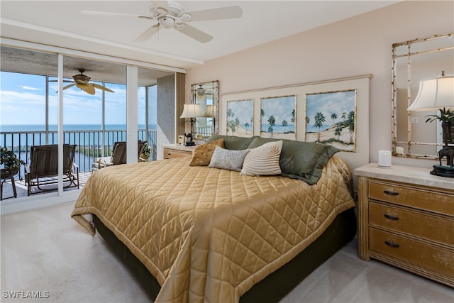 bedroom with a water view, access to exterior, light carpet, ceiling fan, and expansive windows