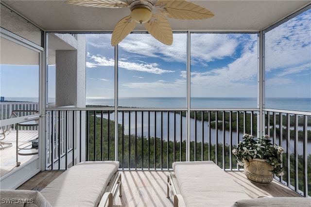 unfurnished sunroom featuring ceiling fan and a water view