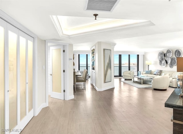 bedroom featuring ornamental molding, wood-type flooring, multiple windows, and a tray ceiling