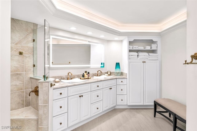 bathroom featuring a tile shower, a raised ceiling, vanity, and ornamental molding