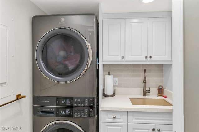 laundry room with sink, cabinets, and stacked washer and clothes dryer