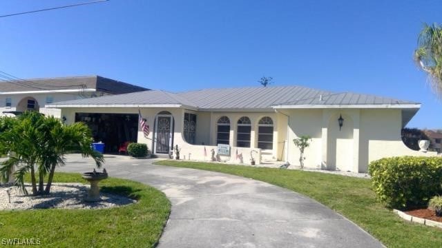 view of front of house featuring concrete driveway, a front lawn, an attached garage, and stucco siding