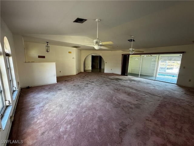 unfurnished living room featuring dark colored carpet, vaulted ceiling, and ceiling fan