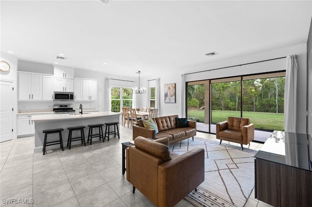 living room with sink, plenty of natural light, light tile patterned flooring, and a notable chandelier