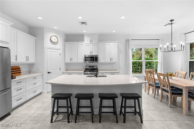 kitchen featuring appliances with stainless steel finishes, sink, a kitchen island with sink, and white cabinets