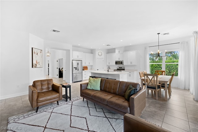 living room featuring a notable chandelier, light tile patterned floors, and sink