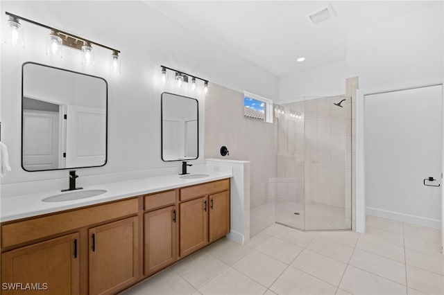 bathroom featuring tile patterned flooring, a tile shower, and vanity