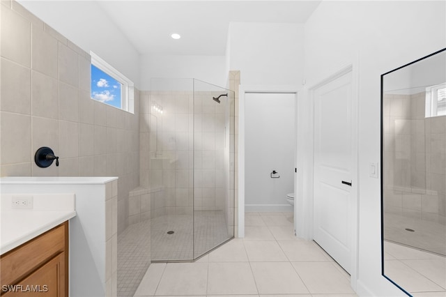 bathroom with a tile shower, tile patterned floors, vanity, and toilet