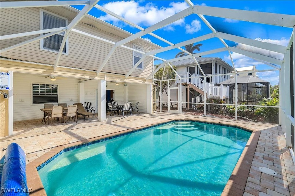 view of pool featuring a patio area, ceiling fan, and a lanai