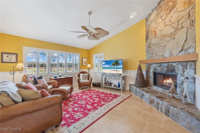 living room featuring a stone fireplace, ceiling fan, and high vaulted ceiling