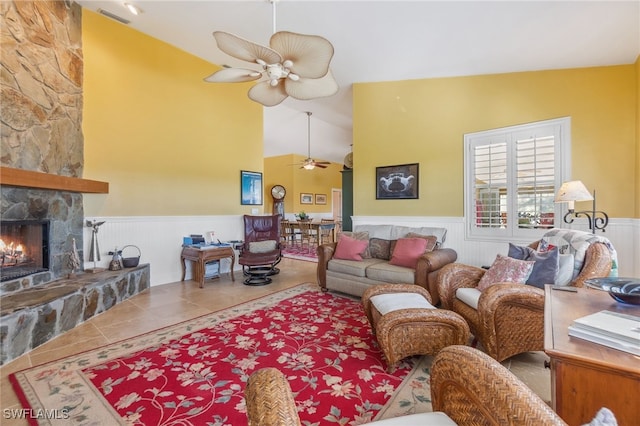 living room with ceiling fan, a stone fireplace, and high vaulted ceiling