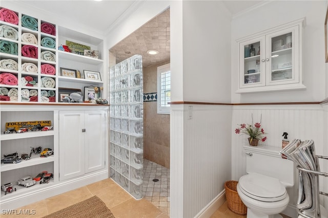 bathroom featuring tile patterned flooring, crown molding, toilet, and walk in shower