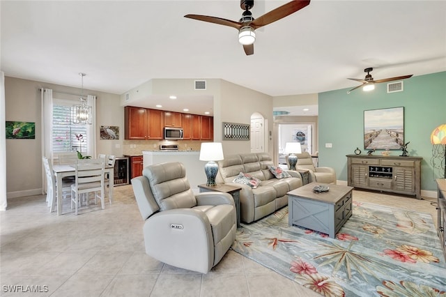 tiled living room with ceiling fan with notable chandelier