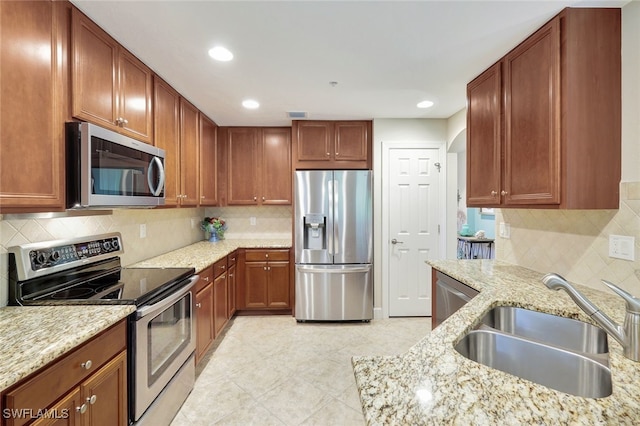 kitchen with tasteful backsplash, light stone countertops, sink, and appliances with stainless steel finishes