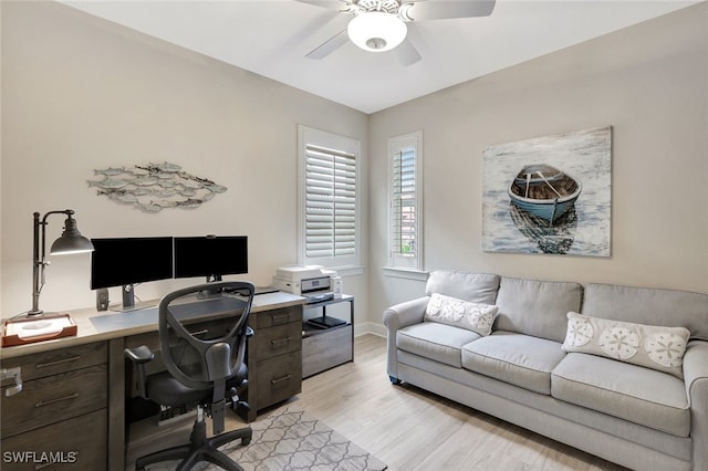 home office with light hardwood / wood-style floors and ceiling fan