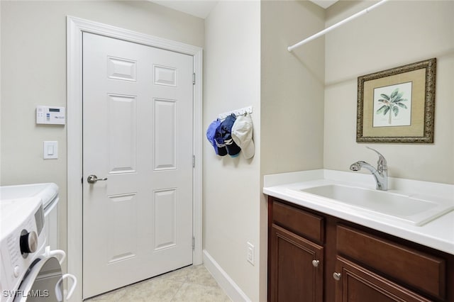 laundry area featuring washer and clothes dryer, sink, light tile patterned floors, and cabinets