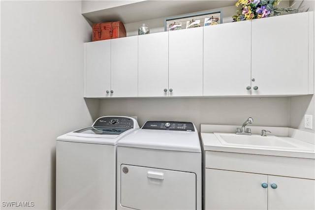 clothes washing area featuring washing machine and clothes dryer, cabinet space, and a sink