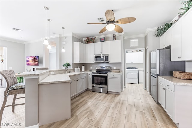 kitchen featuring visible vents, a peninsula, stainless steel appliances, crown molding, and independent washer and dryer