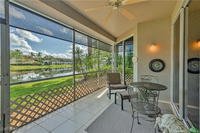 sunroom / solarium featuring ceiling fan and a water view