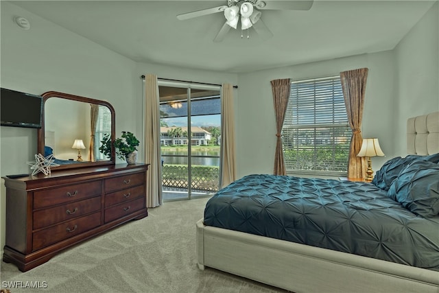 carpeted bedroom featuring access to exterior, ceiling fan, and a water view