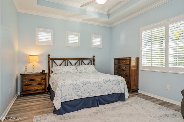 bedroom with hardwood / wood-style floors, ceiling fan, a raised ceiling, and crown molding