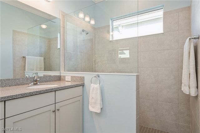 bathroom with a tile shower and vanity