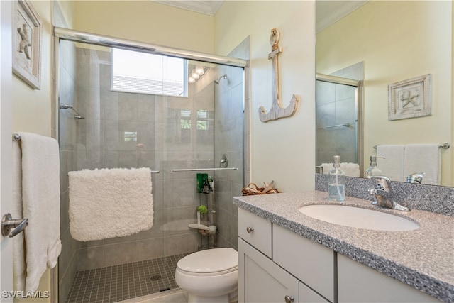 bathroom featuring vanity, toilet, a shower with shower door, and ornamental molding