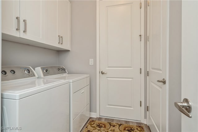 clothes washing area featuring light hardwood / wood-style floors, cabinets, and independent washer and dryer