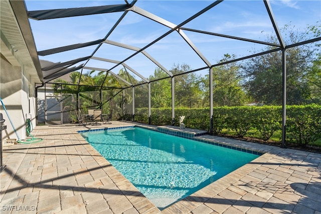 view of pool with glass enclosure and a patio area